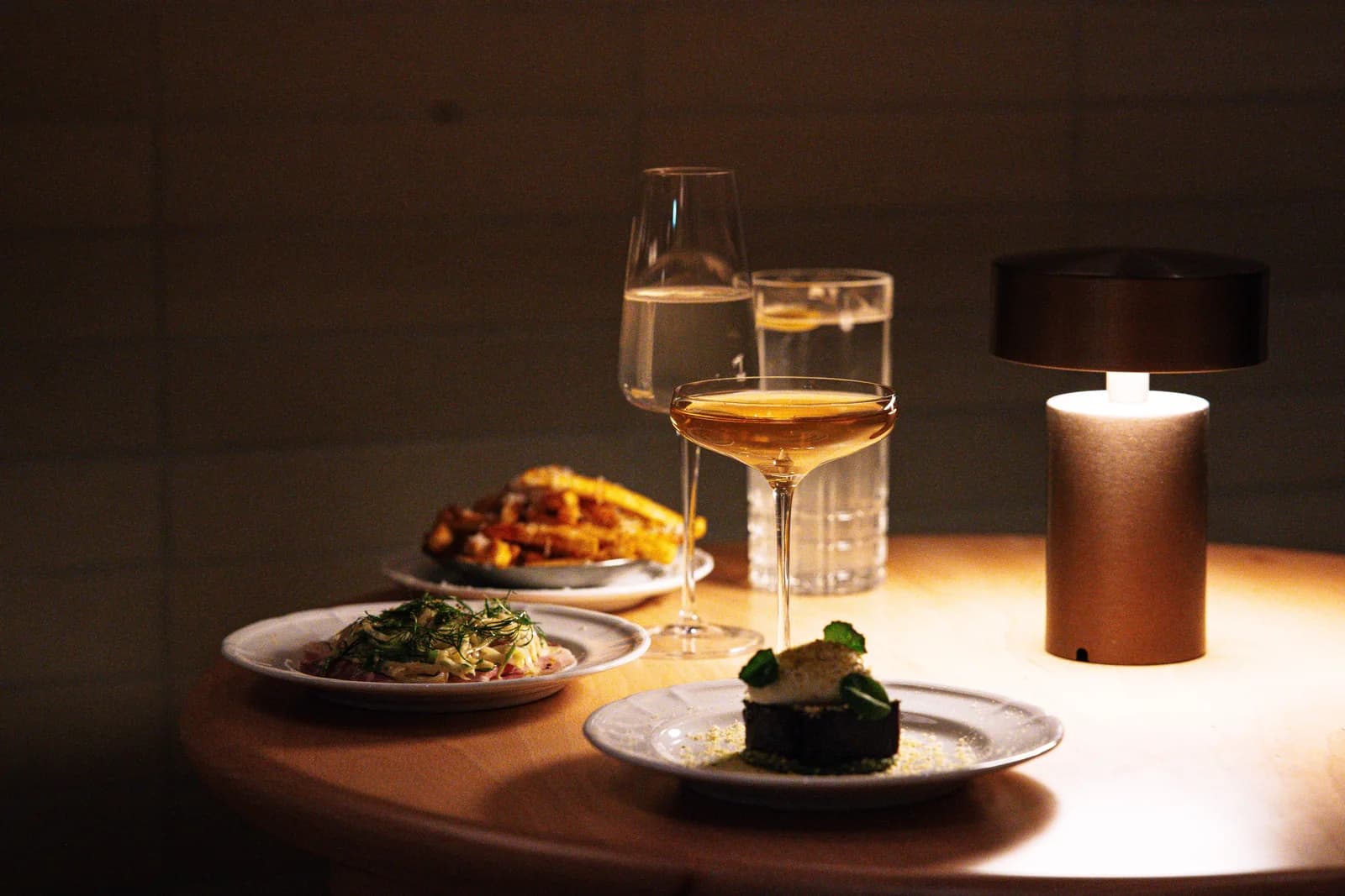Mesa servida con platos, copas y una lámpara encendida