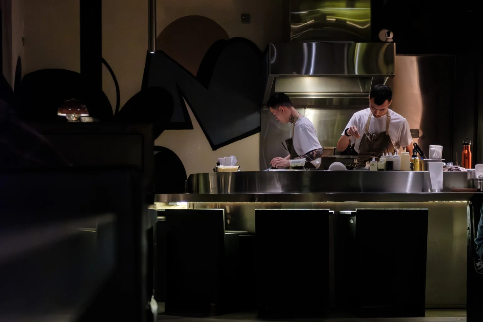 Dos cocineros emplatando en la barra de un restaurante en penumbra